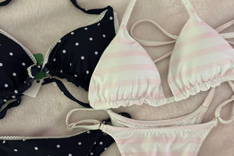 Black polka dot and white striped bikini set on a light background